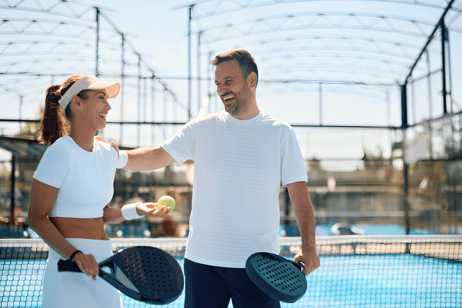 Two happy people playing padel on a court.