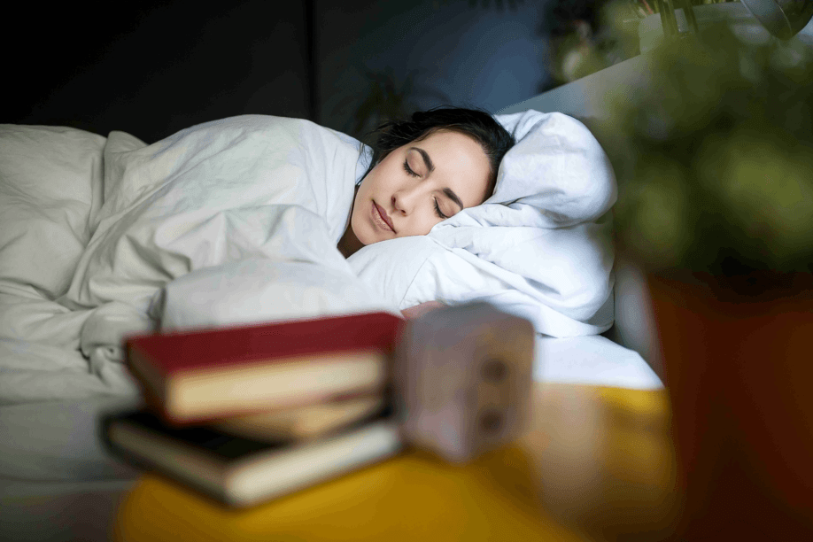 Woman with eyes closed sleeping peacefully in a white bed.