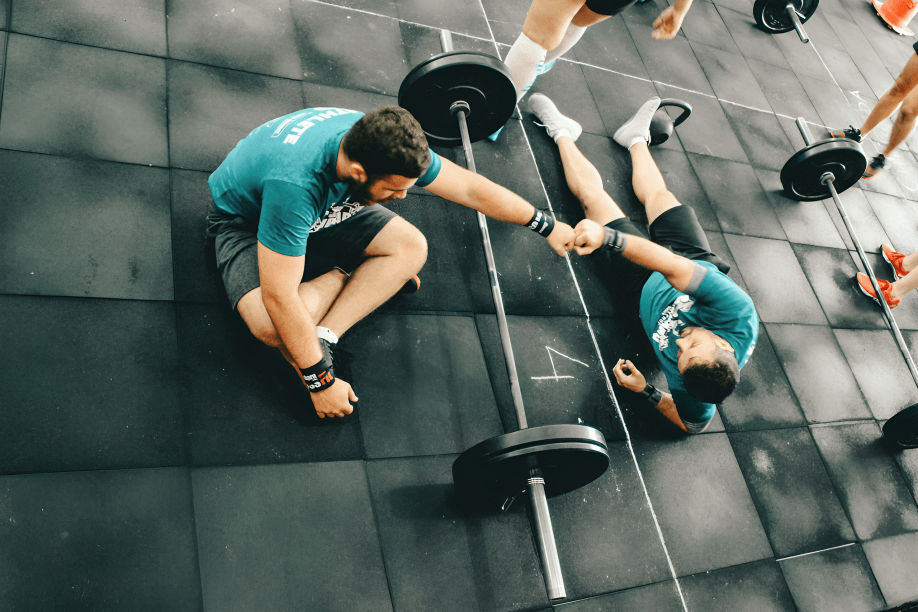 Two male athletes fist-bumping on a gym floor.