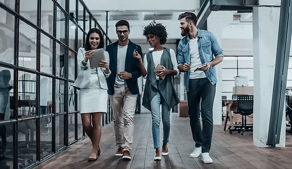 Four young professionals of diverse appearances walk in the office.