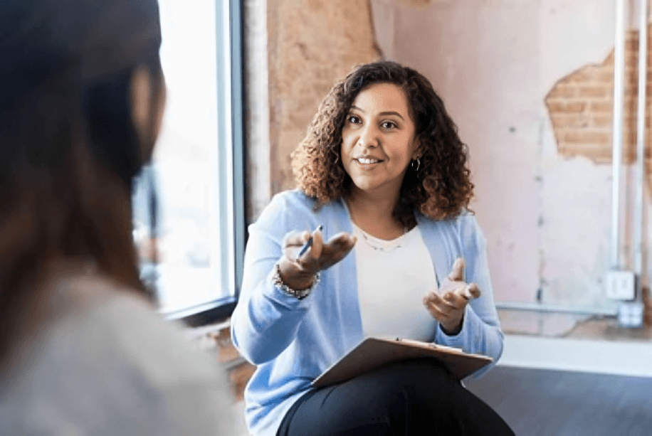 Woman with curly hair talking to another person.