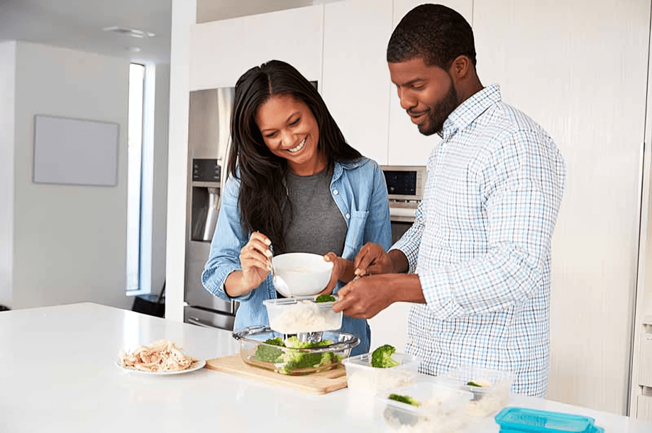 A couple, possibly African, preparing a meal in the kitchen.