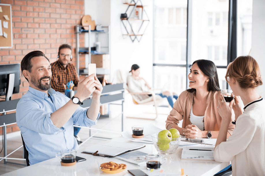 Man taking a picture of smiling colleagues in an office.