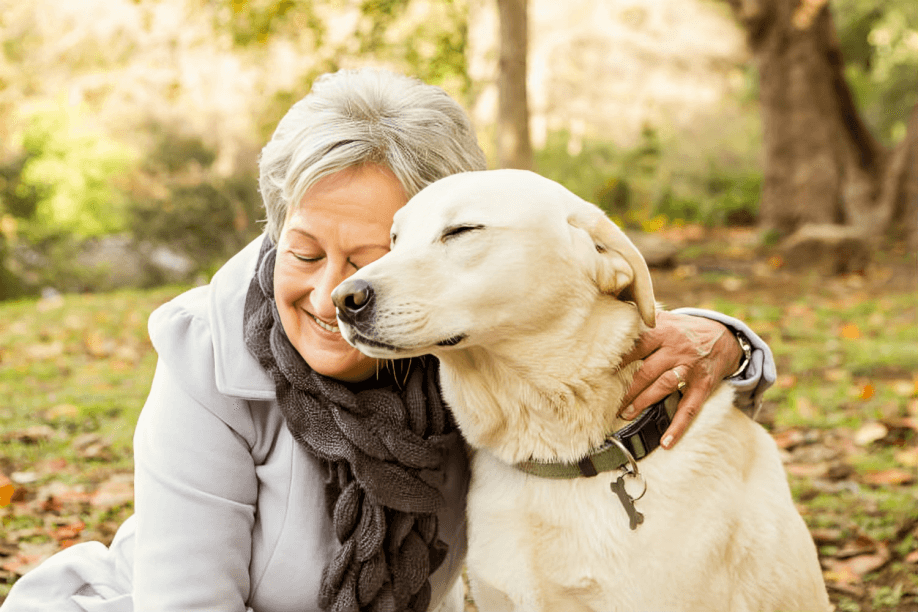 Senior woman embracing a golden retriever dog.