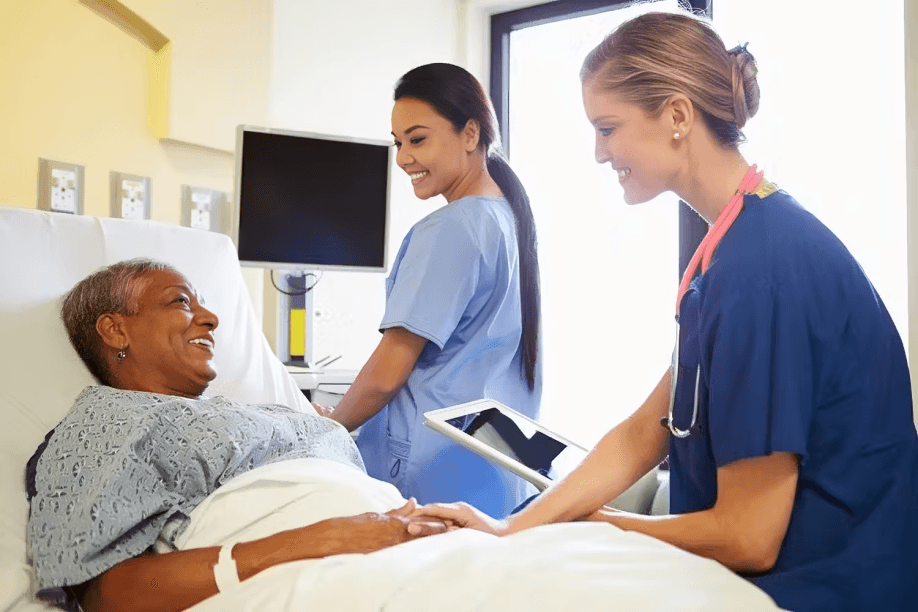 Two nurses caring for a smiling patient.