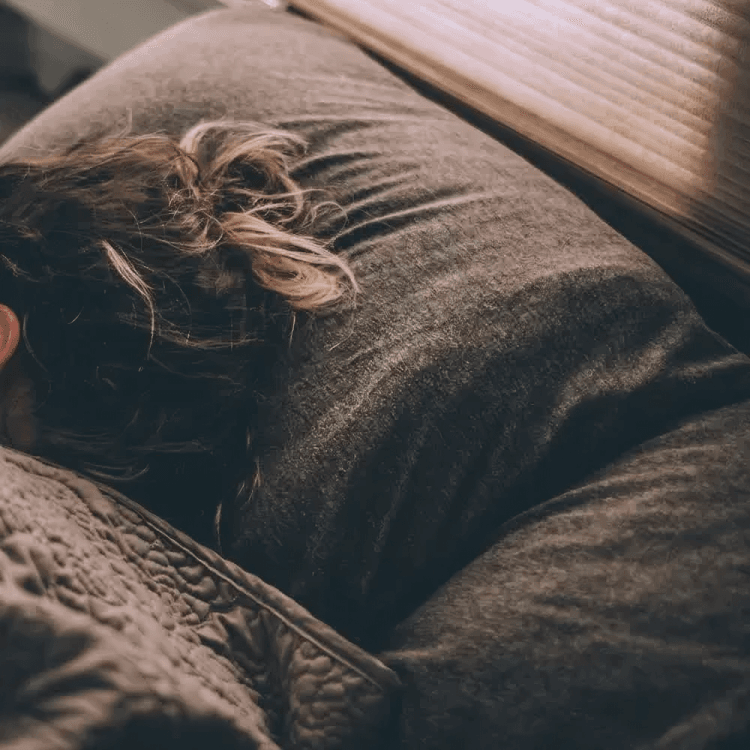 Young woman sleeping on her stomach with her hair in a bun.
