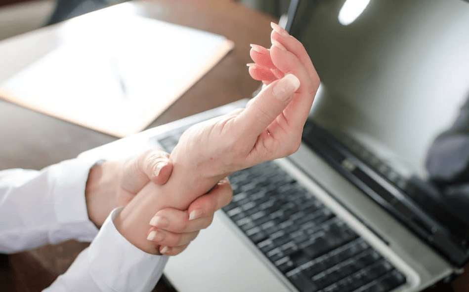 A person experiencing wrist pain while working on a laptop.