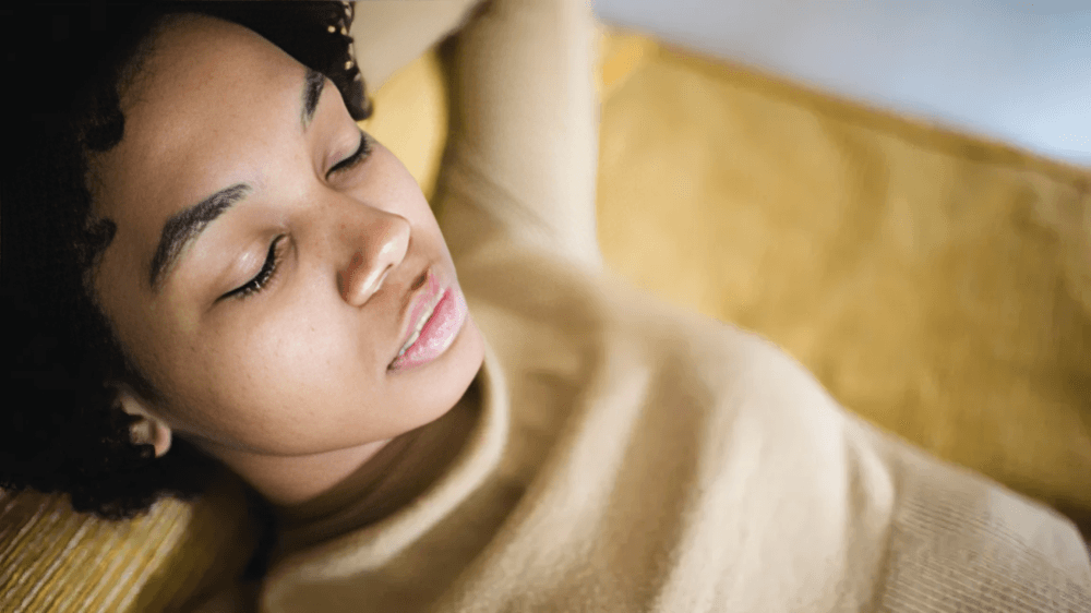 A person with dark skin and curly hair sleeping.