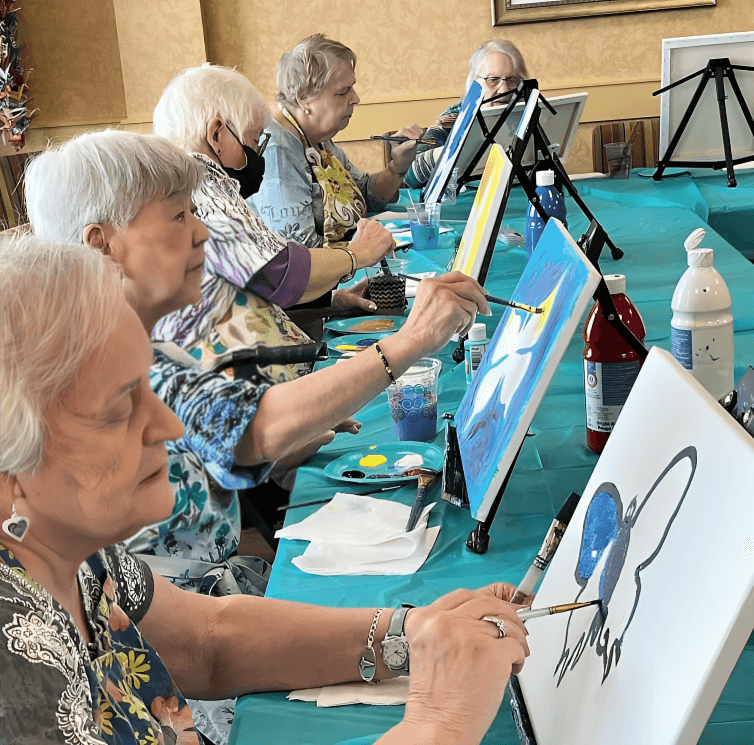 Women at an art class painting on canvases.