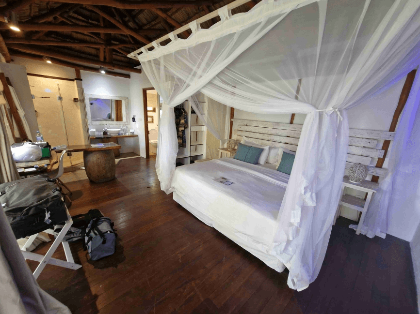 Cozy bedroom with a canopy bed, wooden floors, and a bathroom.