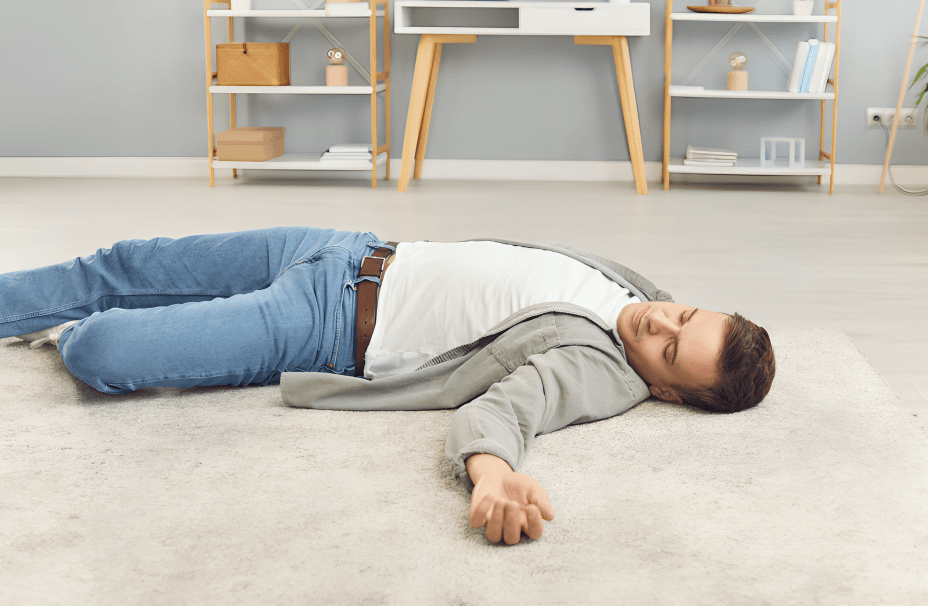 A man lies unconscious on a carpeted floor.