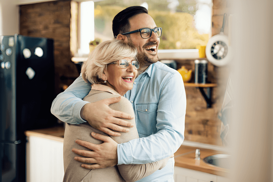 A man and an older woman happily embracing.