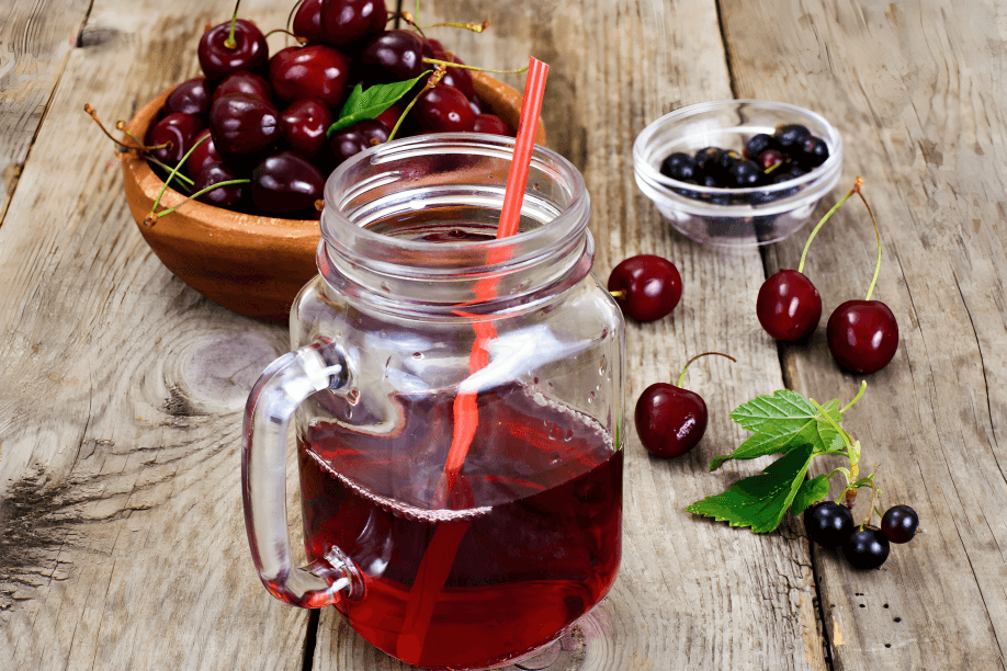 Cherry juice in a jar with fresh cherries and berries.