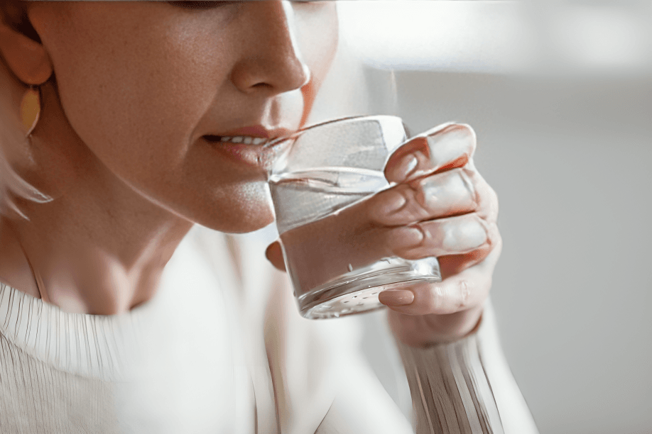 A woman's hands hold a glass of water.