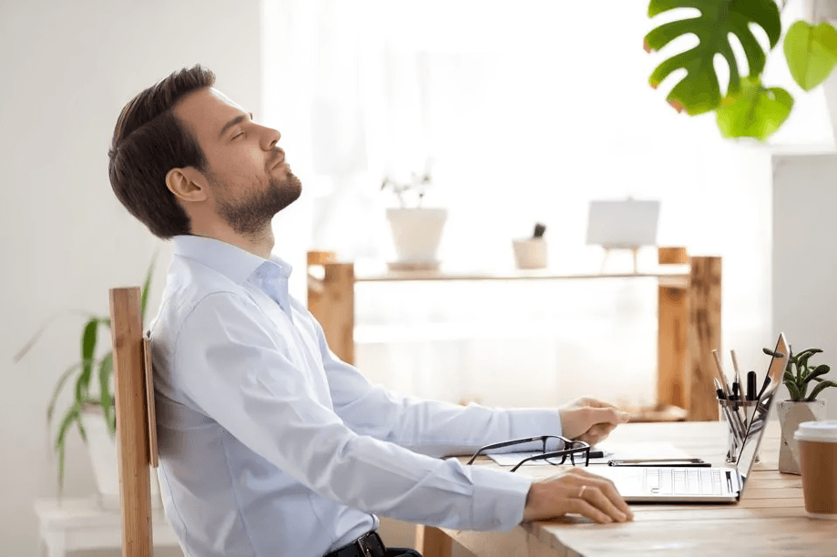 Man relaxing in office chair with eyes closed.