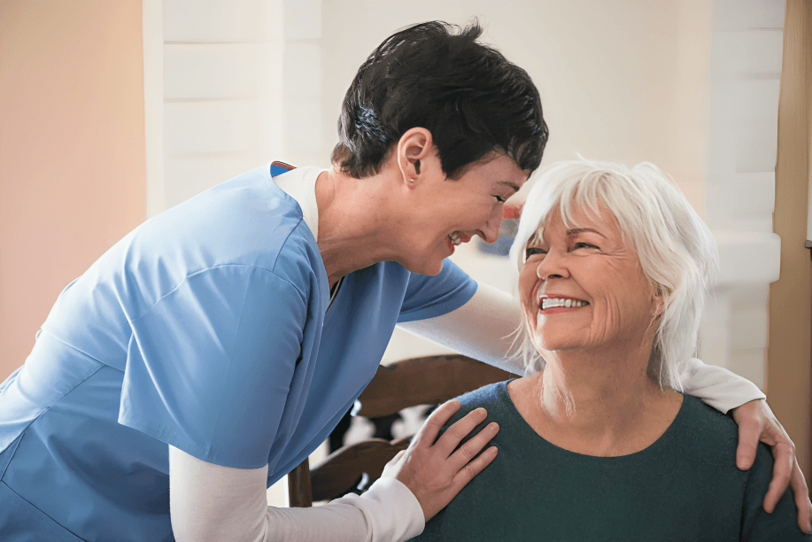 Nurse embracing and smiling with an elderly woman.