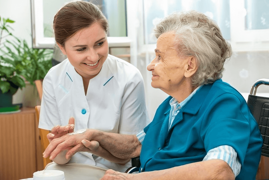 Caregiver applies lotion to senior woman's hand.