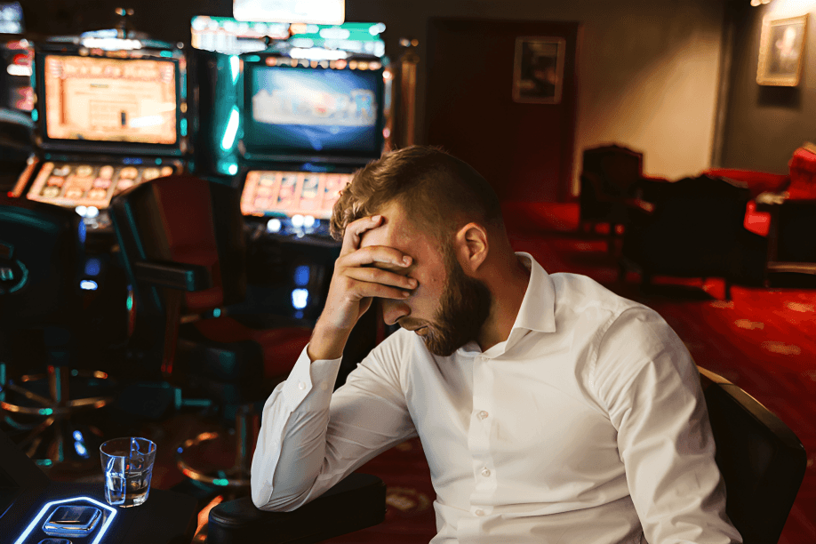 A man with his head in his hand at slot machines.