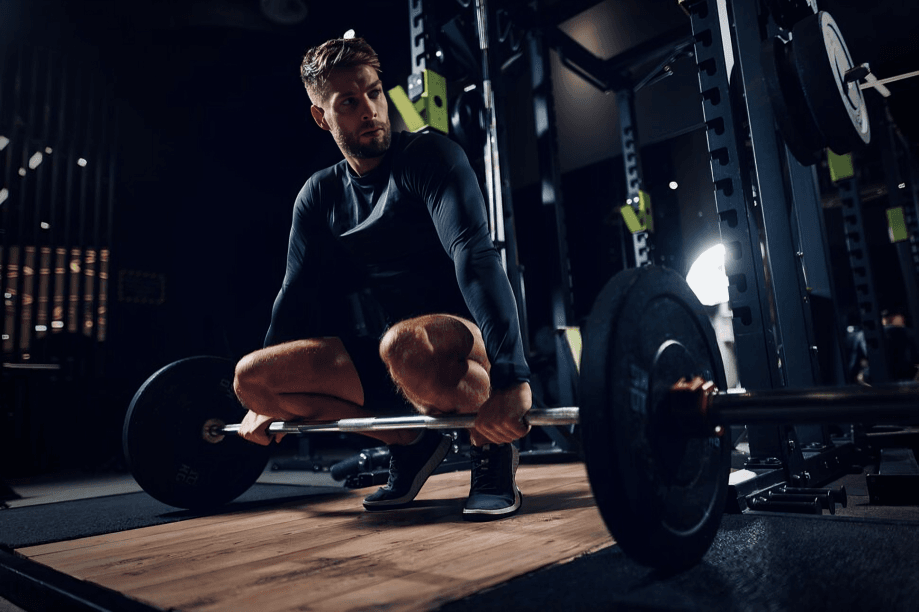 A man preparing to lift a barbell in a gym setting.