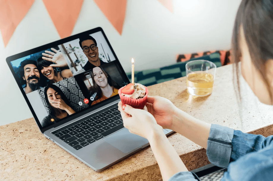 Woman with cupcake celebrating birthday with friends online.