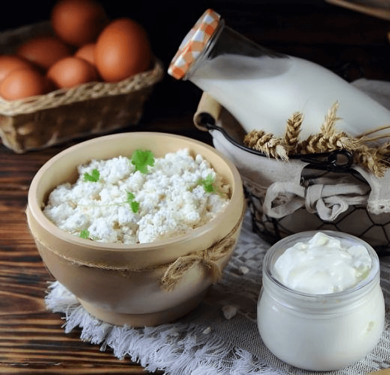 Fresh cottage cheese, milk, and eggs on a wooden surface.