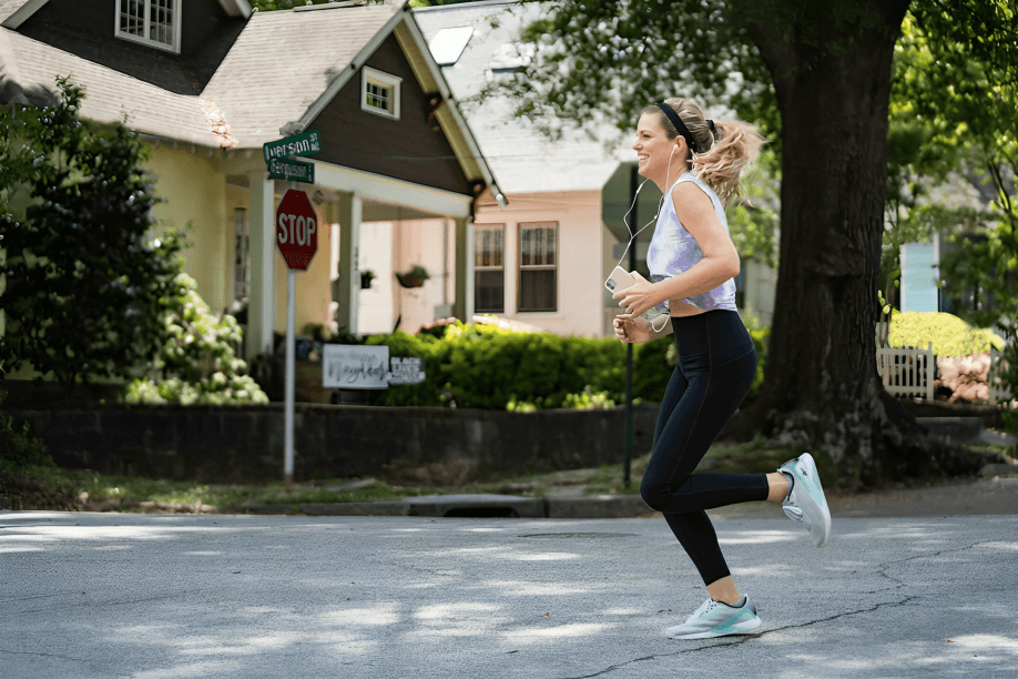 A woman running on a street in front of houses.