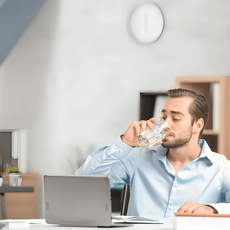 Man in office drinking water while working.
