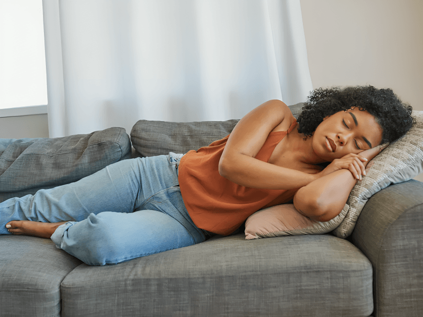 Woman peacefully napping on a comfortable gray couch.