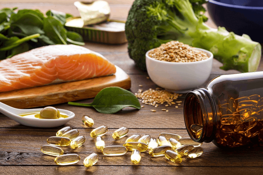 Salmon, broccoli, seeds, oil, and capsules on a wooden surface.