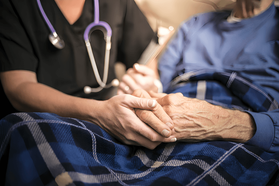 A nurse comforting an elderly patient by holding hands.