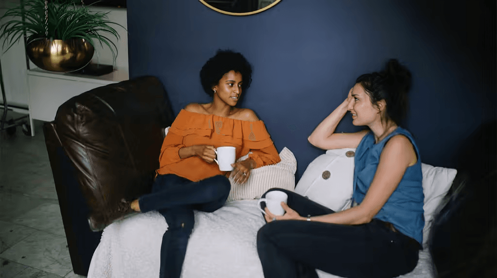 Two women, possibly friends, chatting on a couch.