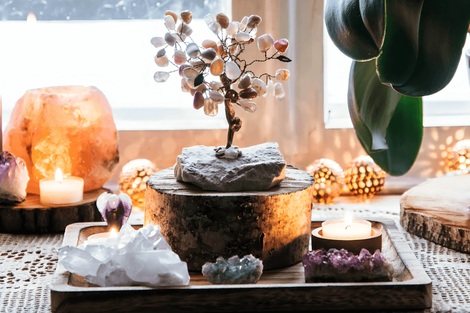 Healing crystals, candles, and an agate tree on a tray.
