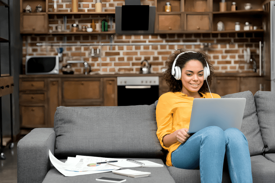 A person with headphones smiles while using a laptop.