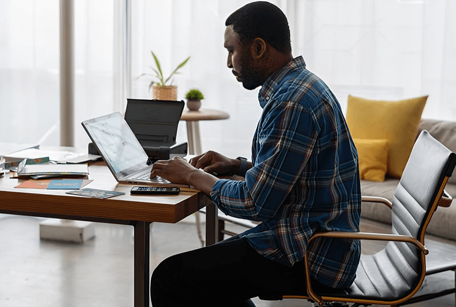 Man working on laptop at bright home office.