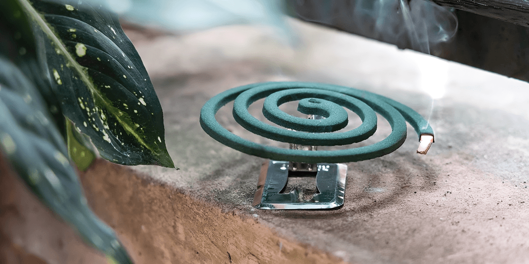 Green mosquito coil burning, emitting smoke.