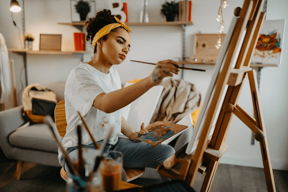 Young woman with yellow headscarf painting on canvas.