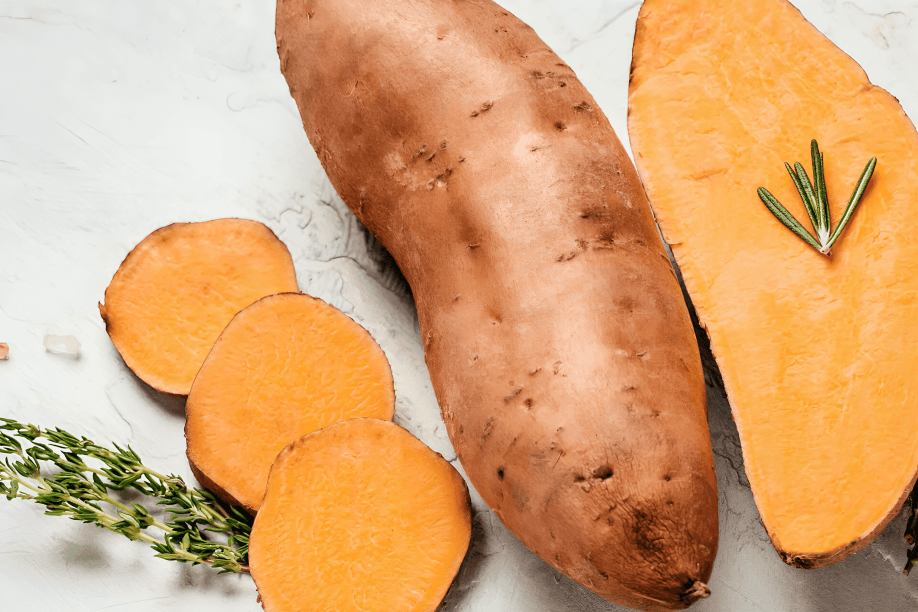 Sweet potato and yam, with rosemary on a white surface.