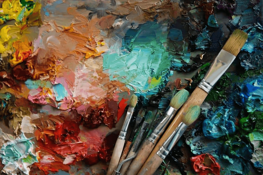 Colorful artist's palette with various paintbrushes and mixed colors.