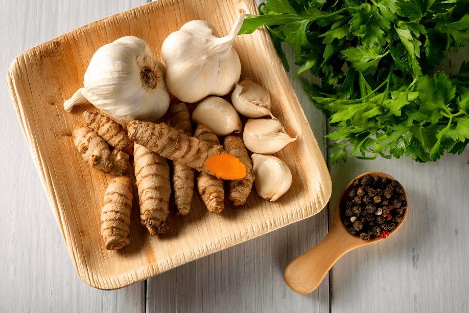 Garlic, turmeric, parsley, and peppercorns on a plate.