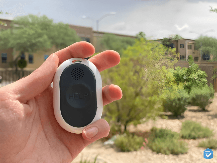 Hand holding white "HELP" button outdoors.
