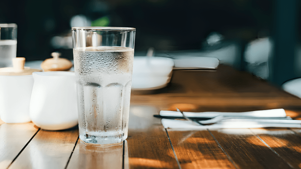 A cold glass of water on a wooden table.