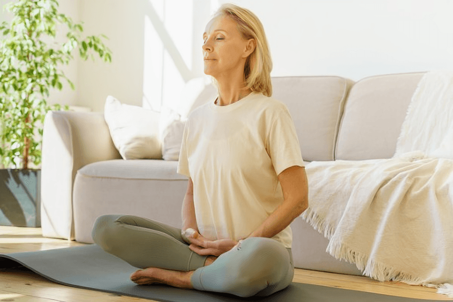 Woman with closed eyes meditating in a living room.