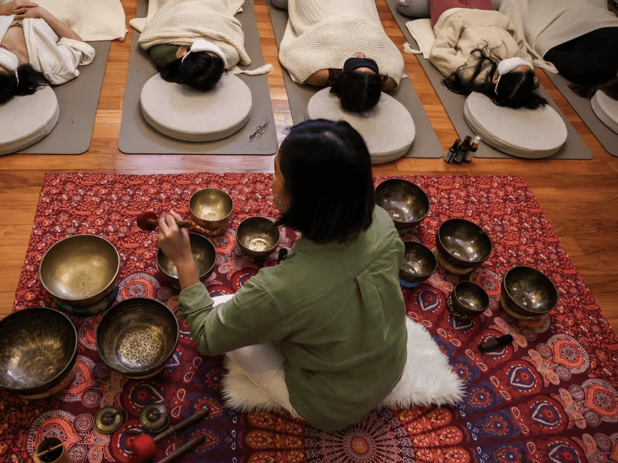 Person playing singing bowls for a sound healing session.