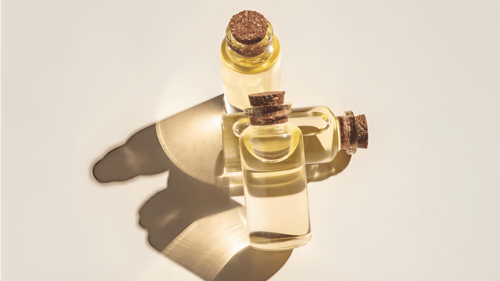 Three corked essential oil bottles with shadows on a light surface.
