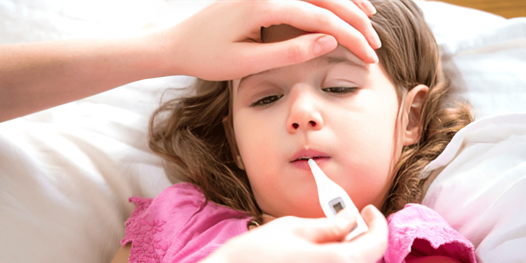 Child with curly hair sneezing, a thermometer in foreground.
