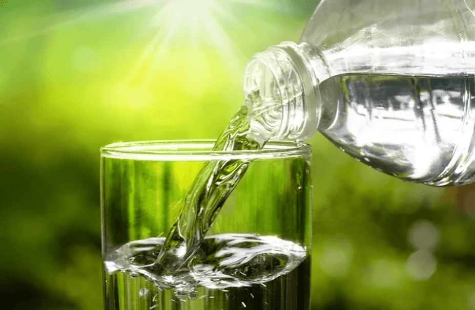 Fresh water pouring from a bottle into a glass outdoors.