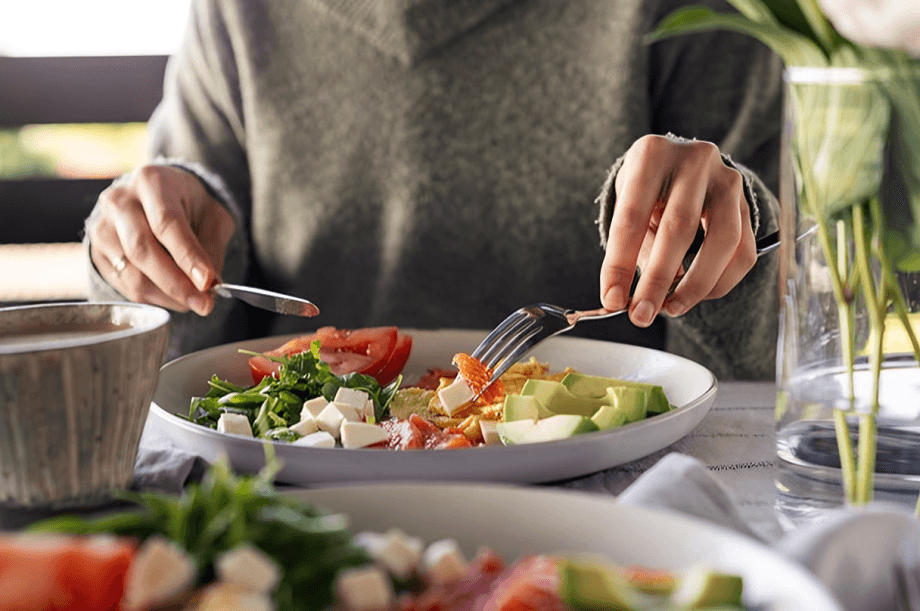 A person eating healthy meal with fork and knife.