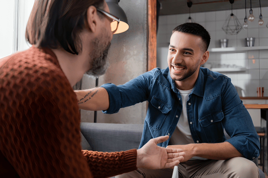 Two men, possibly friends, shaking hands indoors.