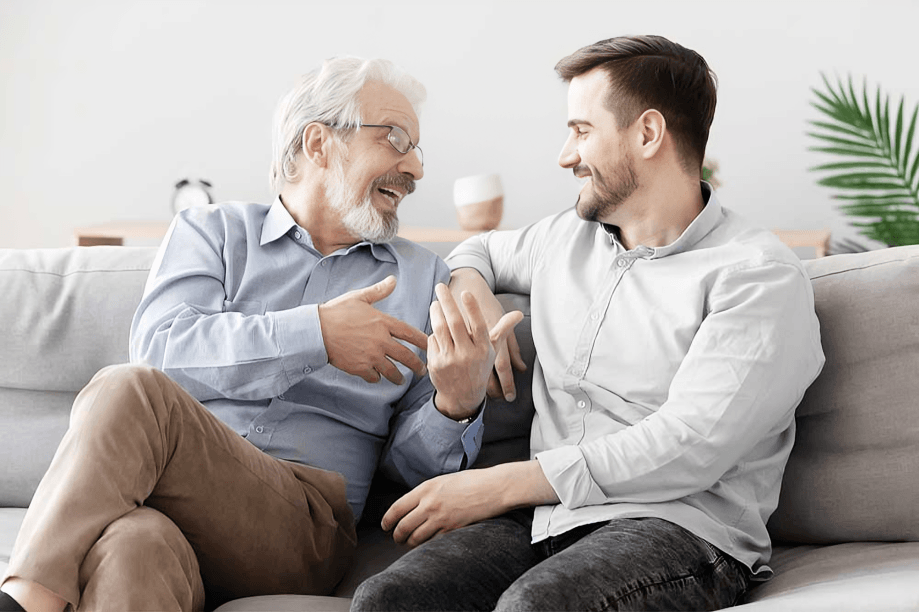 A man laughing with a younger man on the sofa.