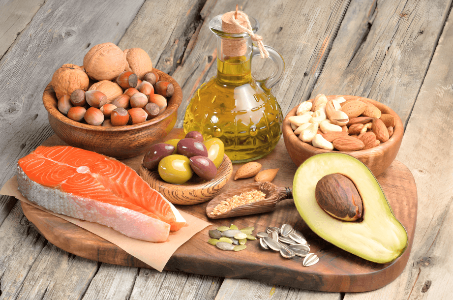 Assortment of healthy fats: salmon, nuts, avocado, and oil.